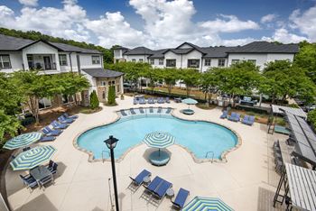 A large swimming pool surrounded by lounge chairs and umbrellas.